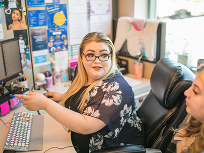 A virtual receptionist at her desk being trained by her boss