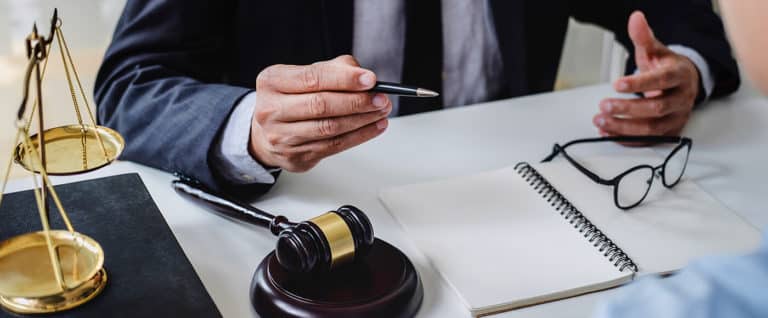 Lawyer hands and gavel on desk.