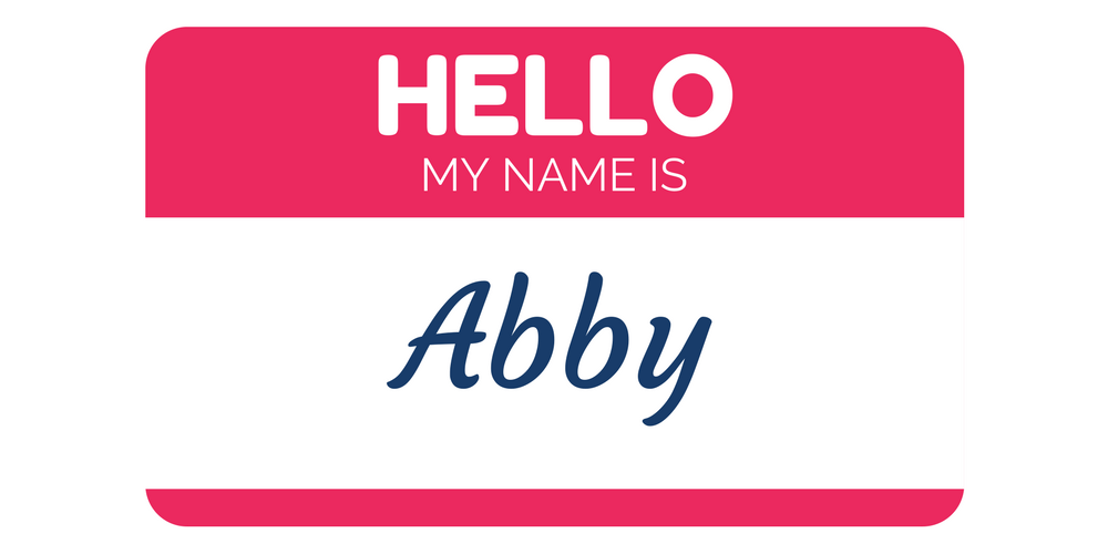 A red and white name tag with the words HELLO MY NAME IS in bold letters and Abby written in cursive script.