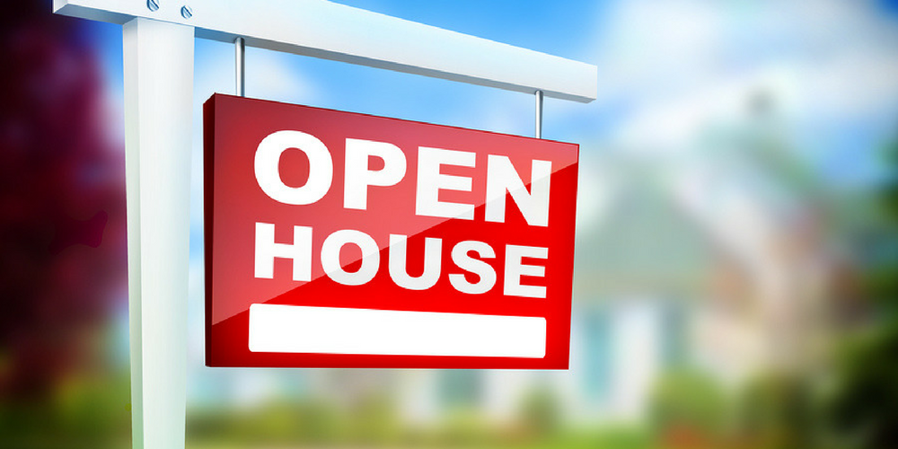 A red and white Open House sign is displayed outside, with a blurred house and greenery in the background. The sign is mounted on a white post.