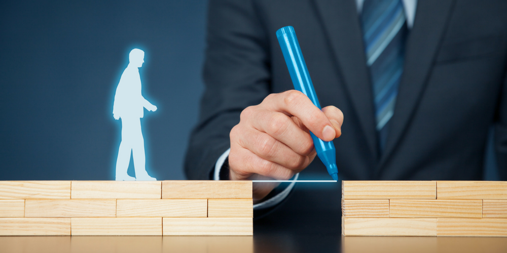 A person in a suit draws a blue line between two stacks of wooden blocks, with a glowing silhouette of a human figure walking toward the gap.
