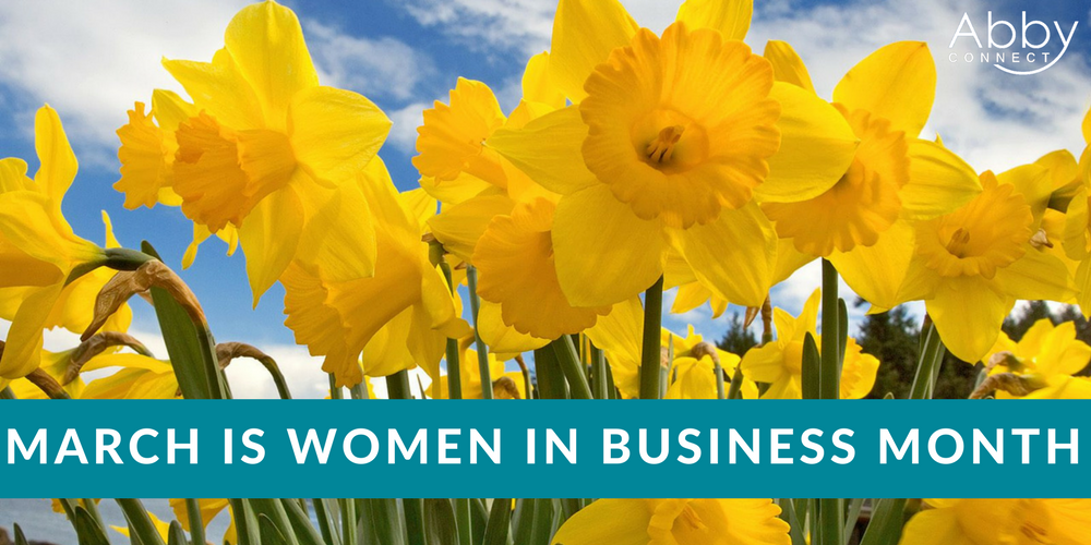 Bright yellow daffodils in bloom under a blue sky with clouds. A teal banner across the bottom reads, March is Women in Business Month. The Abby Connect logo appears in the top right corner.