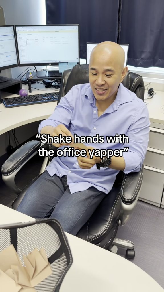 A smiling team member in a blue shirt at his desk in the Abby Connect office as the office yapper prompt is read
