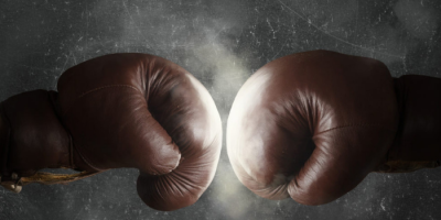 Two brown boxing gloves collide in the center of the image, creating a burst of light and dust against a dark, textured background—symbolizing the dynamic connection and impact of Abby Connect.