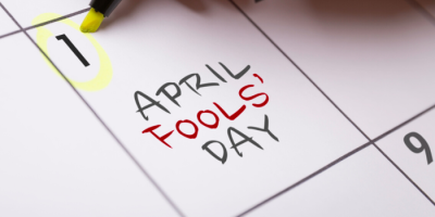 A calendar page with the number 1 circled in yellow and the words April Fools Day written in red and black across the date. A yellow highlighter marks the date.