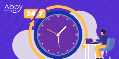 A person sits at a desk with a laptop, beside a large clock and a 24/7 sign. The Abby Connect logo appears in the top left corner, suggesting round-the-clock service.