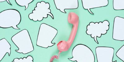 A pink retro telephone handset lies on a mint green background surrounded by various empty white speech and thought bubbles outlined in black.