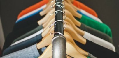 A close-up view of wooden hangers holding various colorful shirts, neatly arranged on a clothing rack.