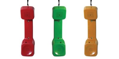 Three vintage telephone handsets in red, green, and yellow are hanging vertically side by side against a white background. Each handset has a cord attached at the top.
