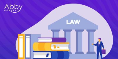 Illustration of a person in business attire holding a briefcase, standing near large law books and a courthouse labeled LAW, representing Top Lawyers, with the Abby Connect logo in the top left corner against a purple background.