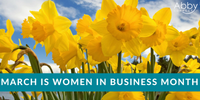Bright yellow daffodils in bloom under a blue sky with clouds. A teal banner across the bottom reads, March is Women in Business Month. The Abby Connect logo appears in the top right corner.